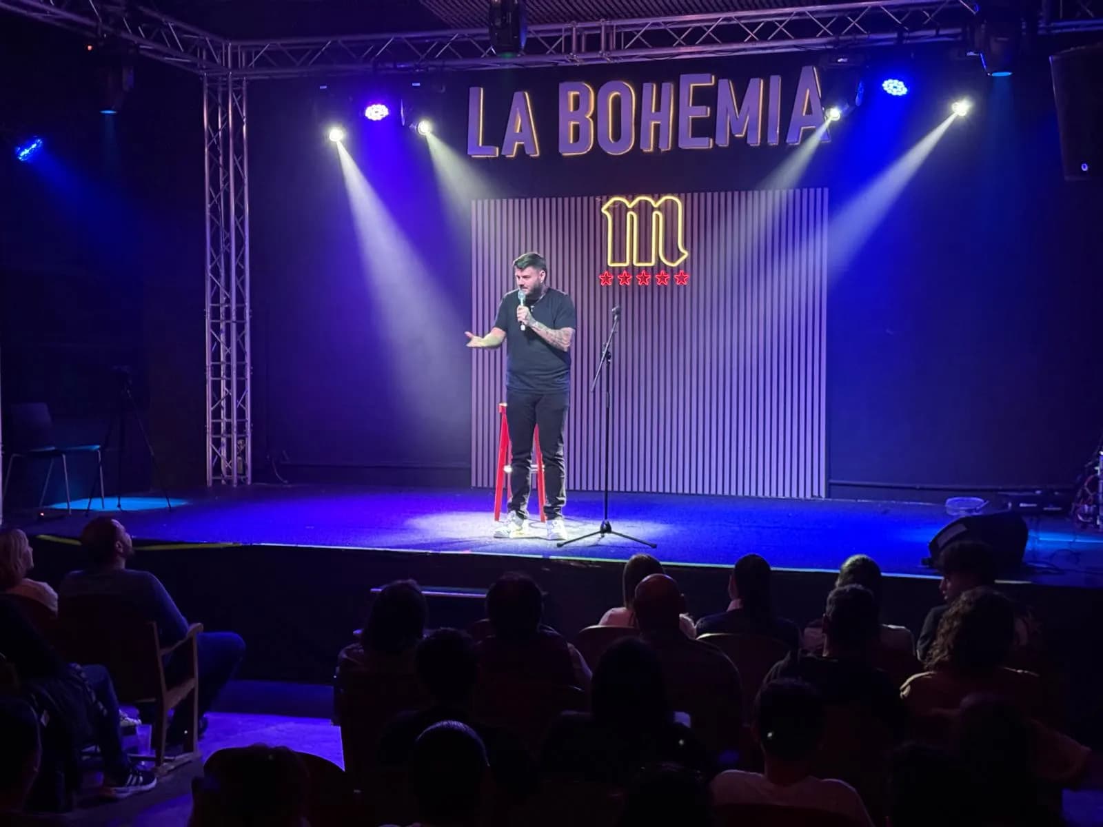 Juanjo Albiñana on the La Bohemia stage with blue spotlights, the truss structure and the audience in front