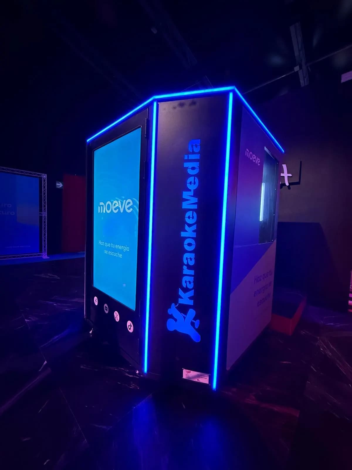 Cabina de karaoke de KaraokeMedia amb perfils de llum blava i la pantalla amb el logo de Moeve