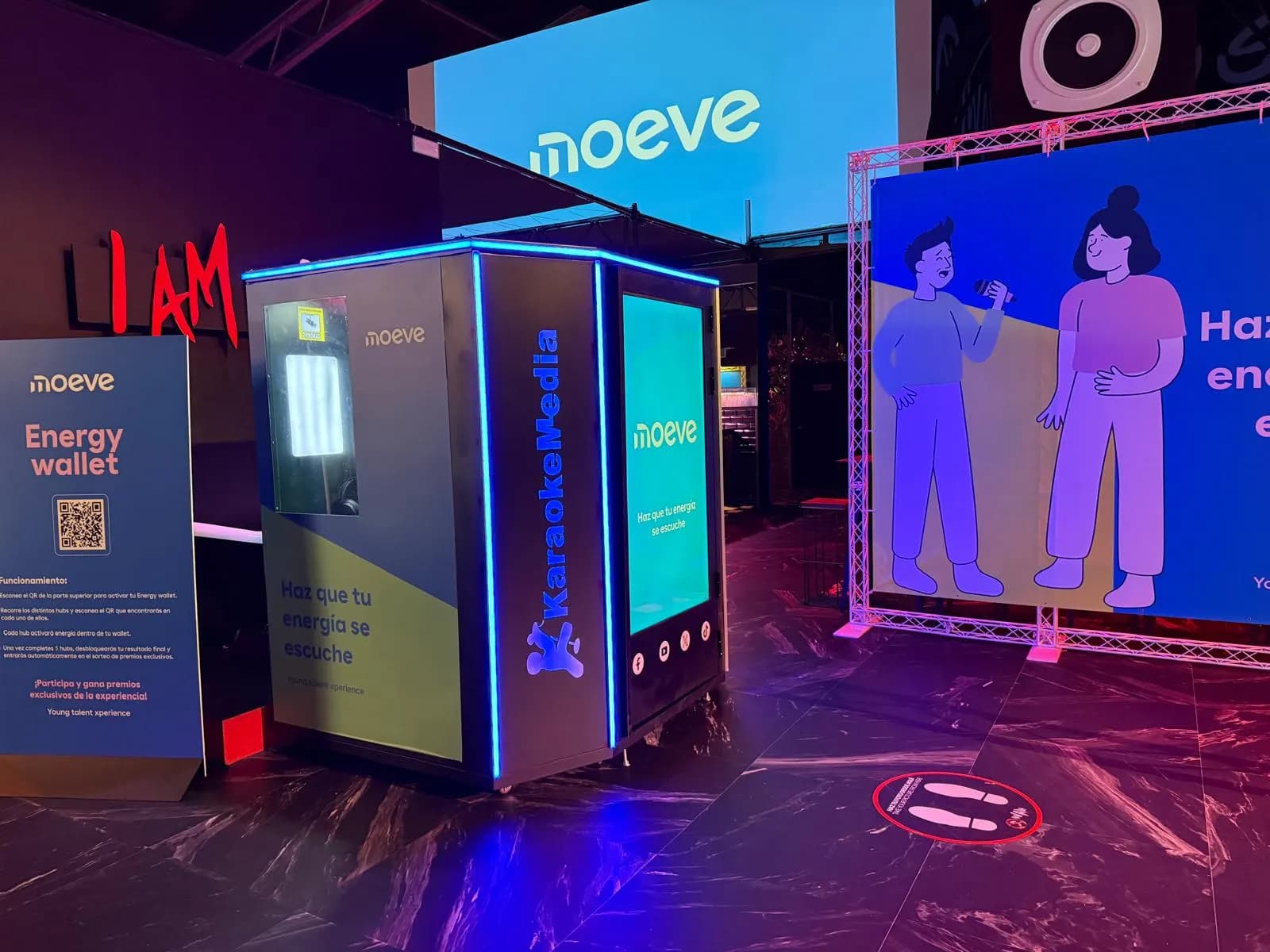 Cabina de karaoke entre el panell «Energy wallet» de Moeve i el photocall, amb el logo i el lema al lateral